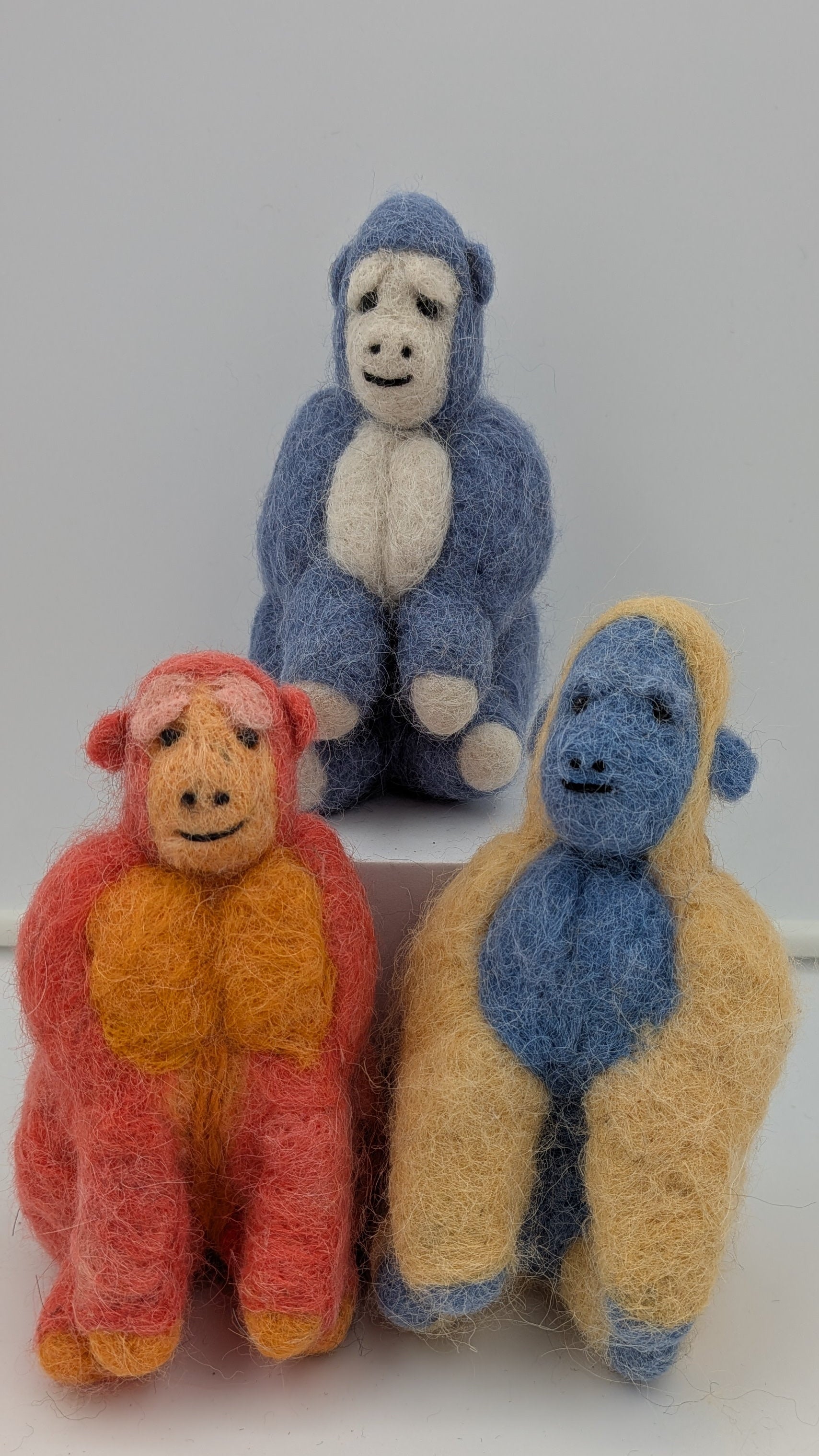 Three colorful monkey figurines on a white surface