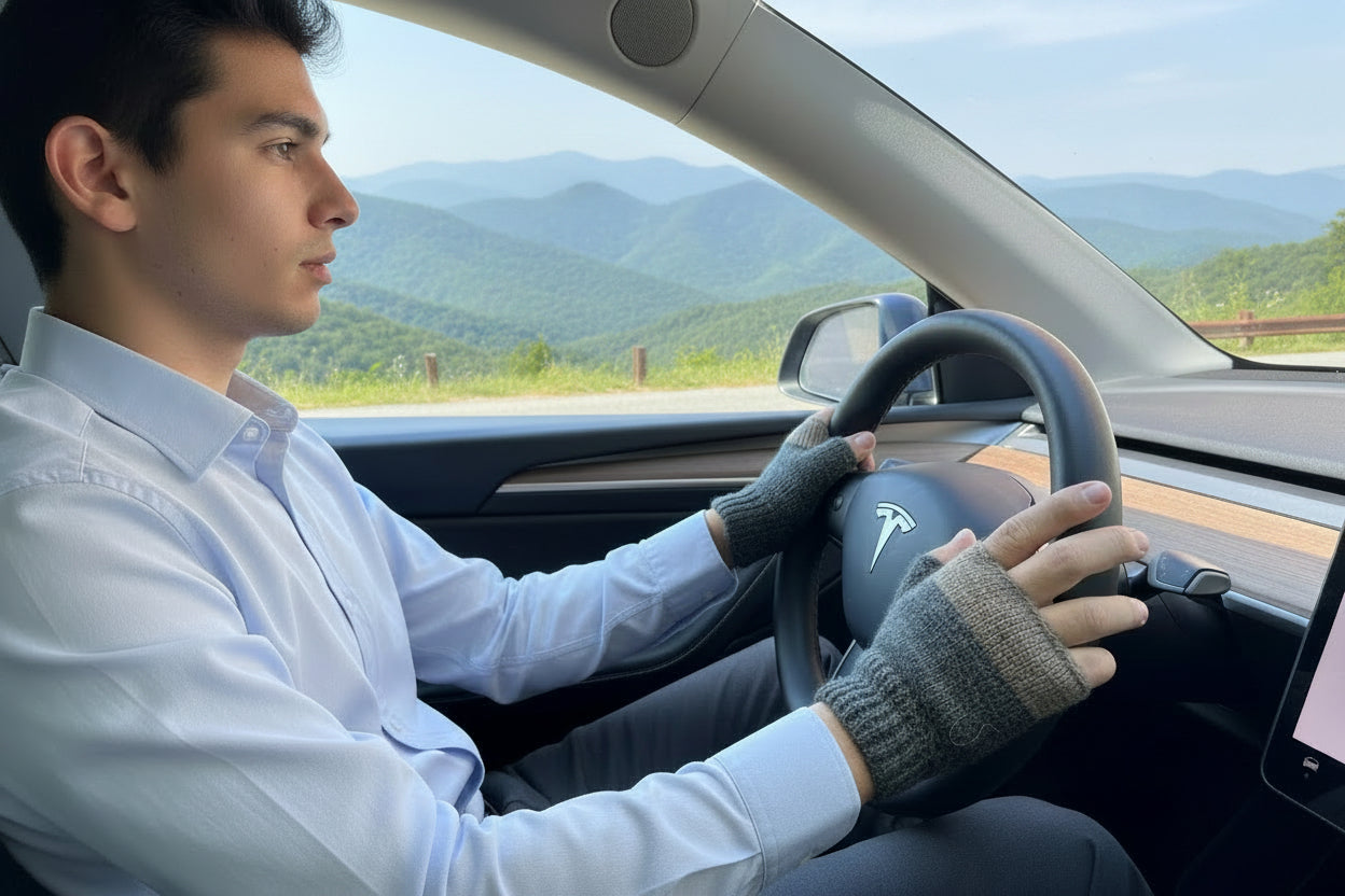 A man with a gray beard wearing a gray t-shirt and fingerless knit gloves sits in the driver&