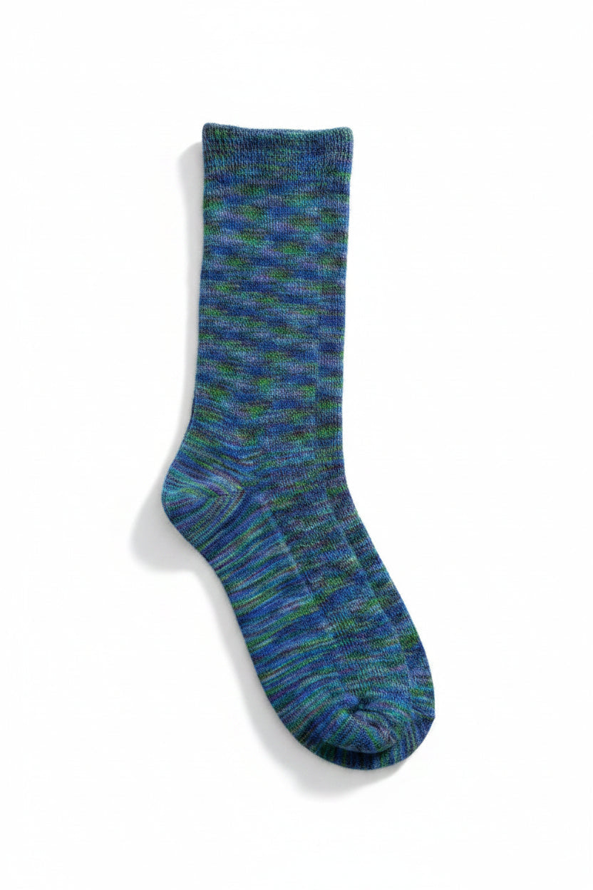 A single knit sock in a variegated blue and green pattern, laid flat on top of a brown cardboard box.