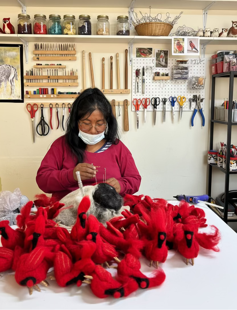 Person working on red plush felted sculpture with her art studio in the background
