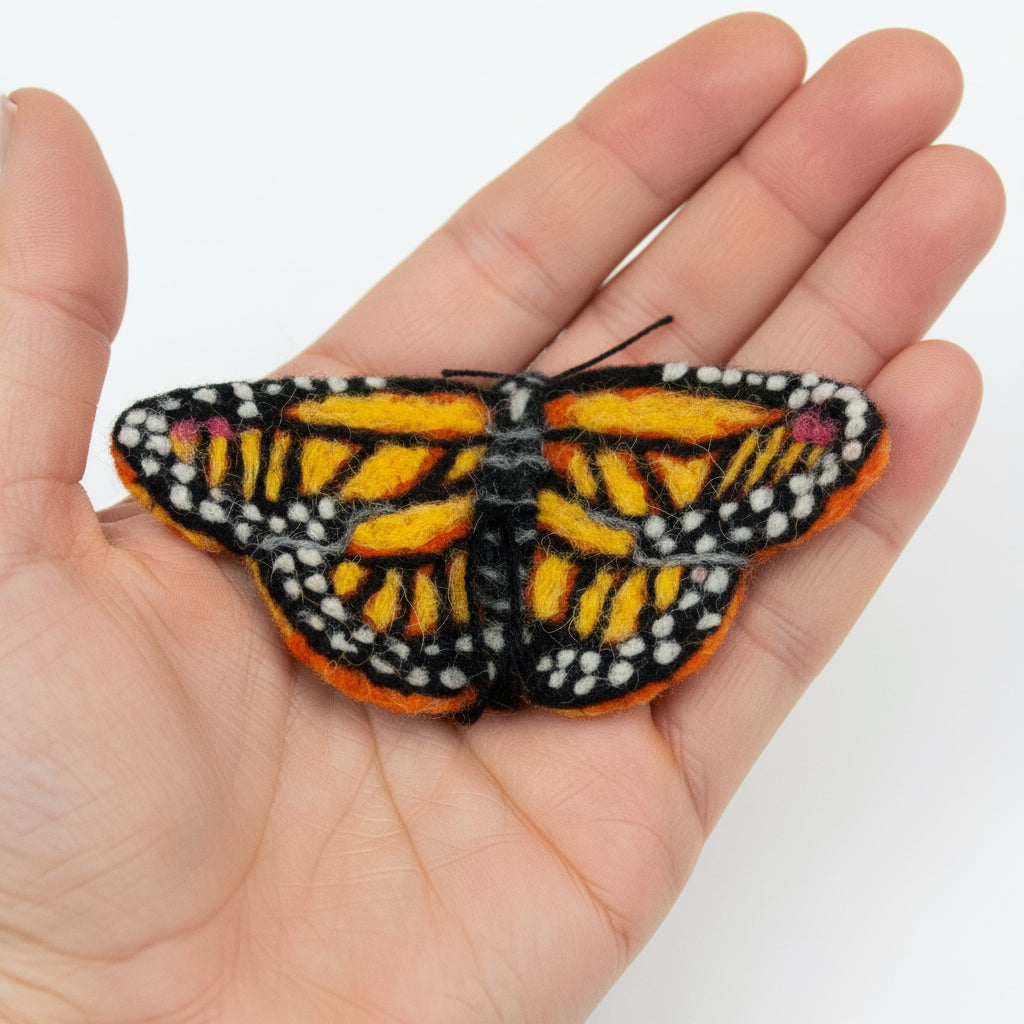 Felted butterfly toy with orange, black, and white pattern on a white background