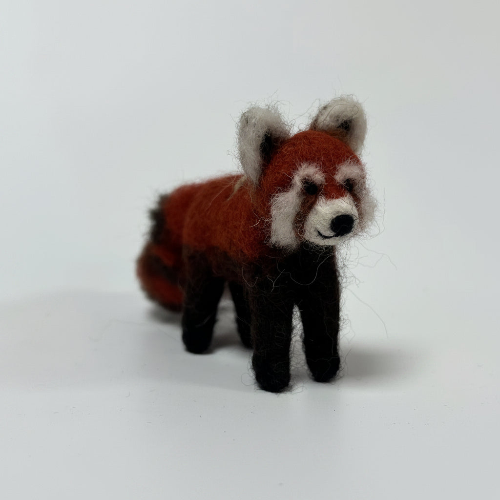A small felted wool red panda figurine standing on a plain white studio background.