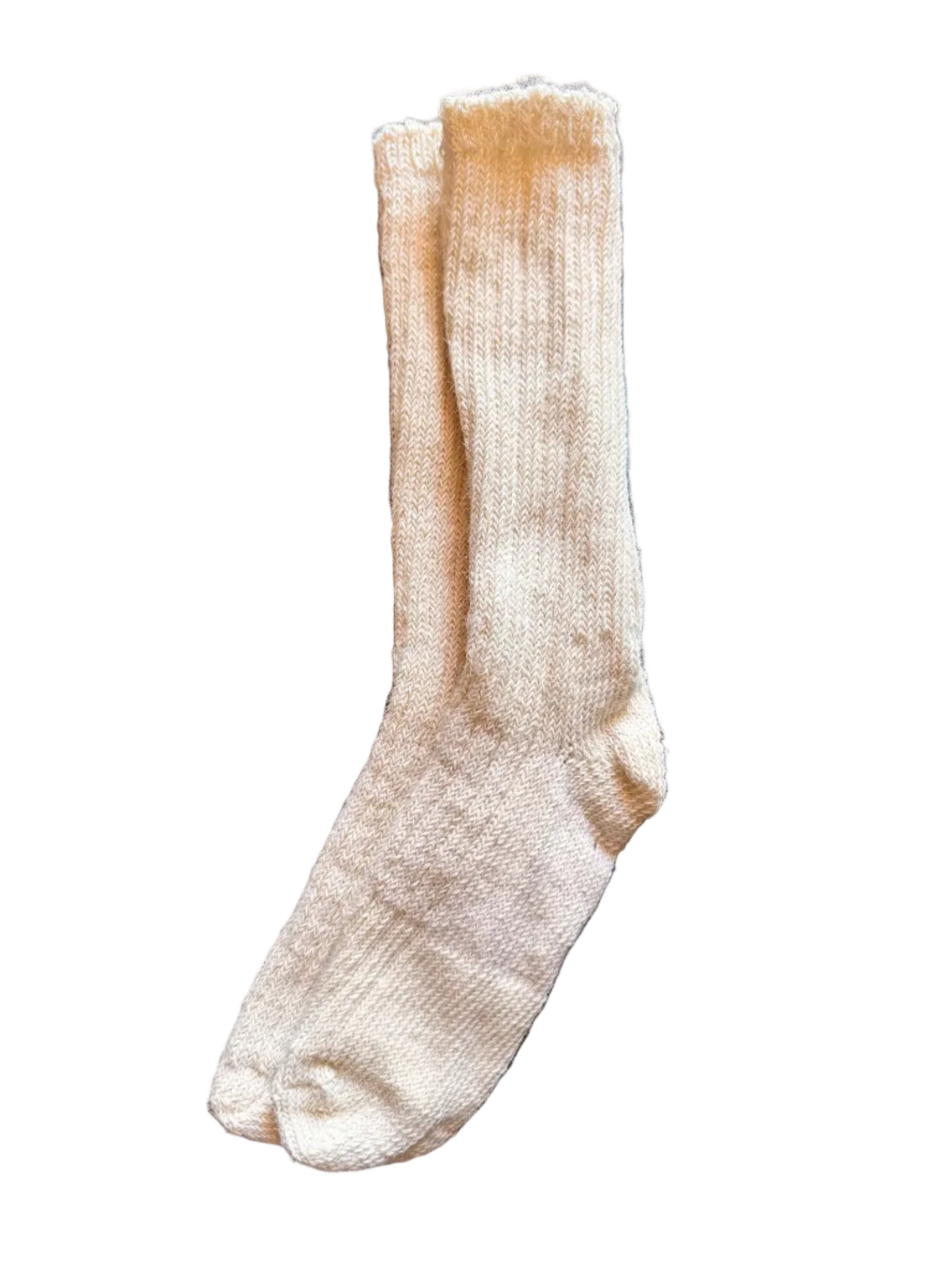 A single cream-colored knit sock laid flat on a dark gray stone tile surface.