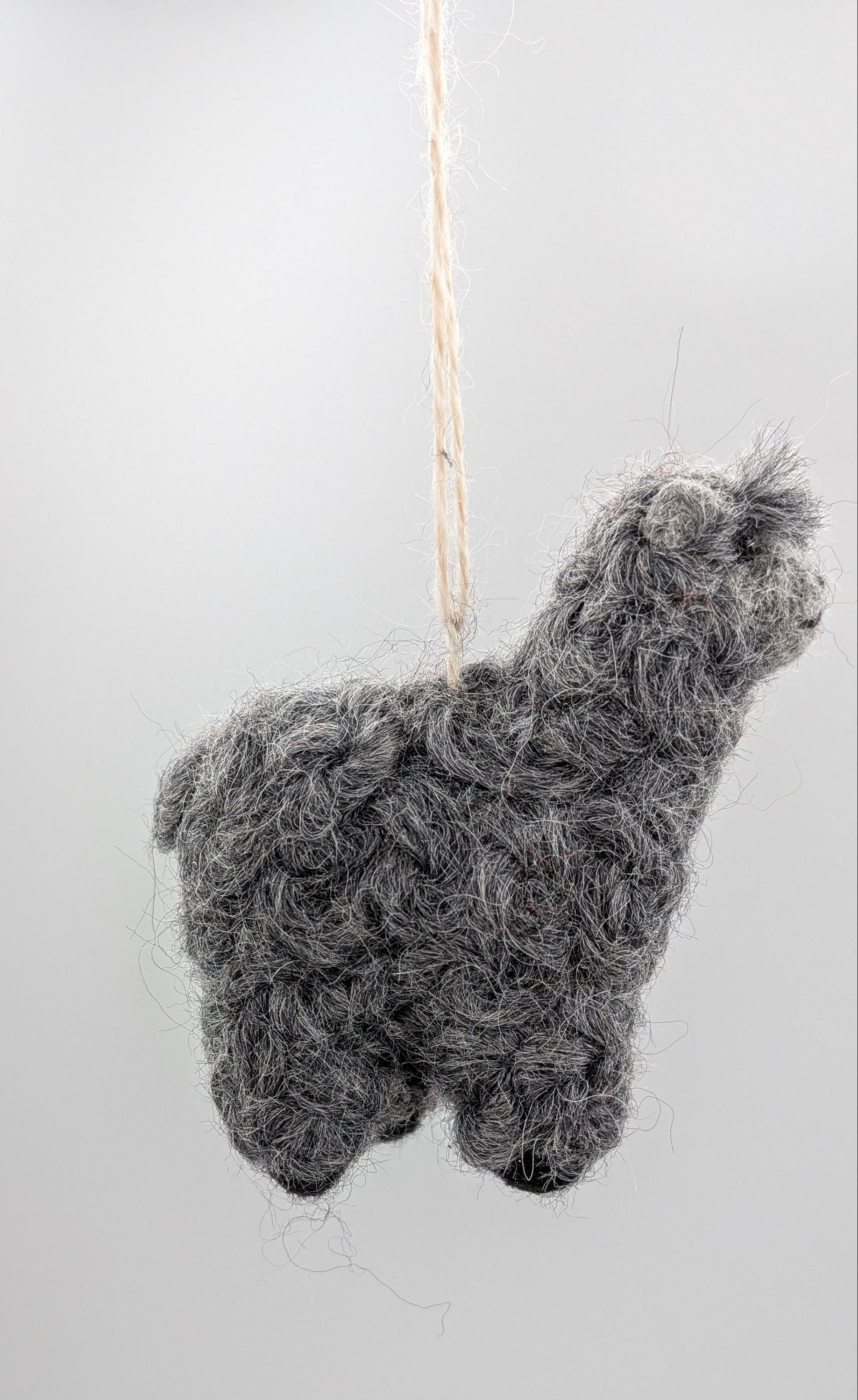A small gray alpaca-shaped hanging ornament made from curly wool or felt, suspended by a thin string against a plain light background.