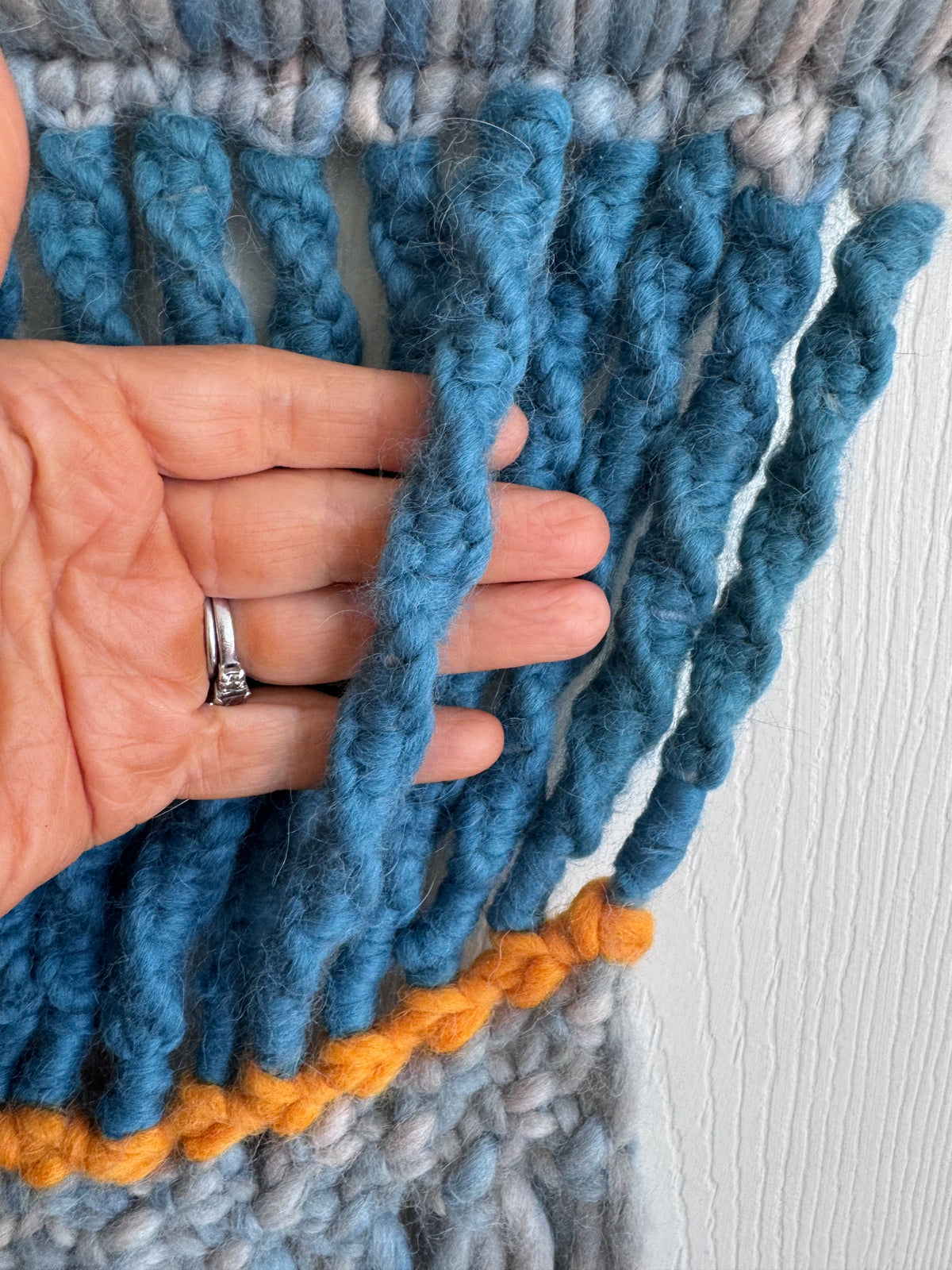 hand holding and showing detail of macrame alpaca fiber art