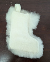 White fuzzy stocking toy on a dark wooden surface