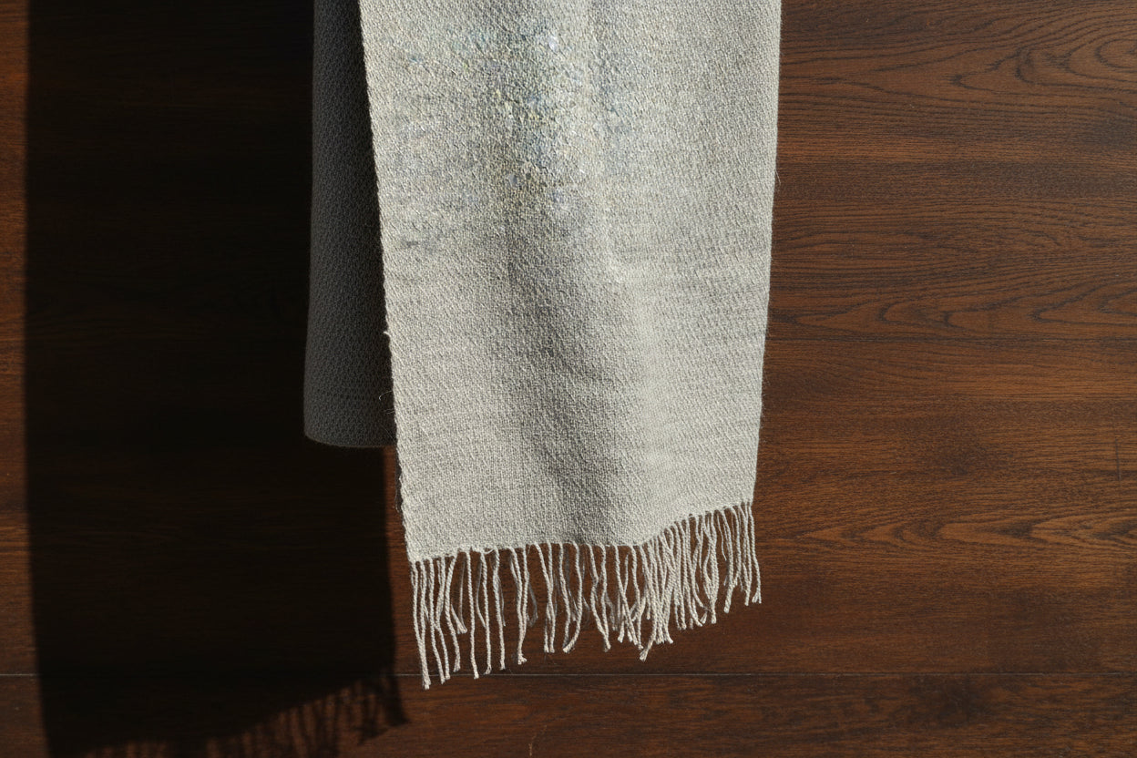 Gray and pearl textured light weight scarf with fringes on a wooden surface