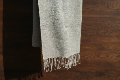 Gray and pearl textured light weight scarf with fringes on a wooden surface