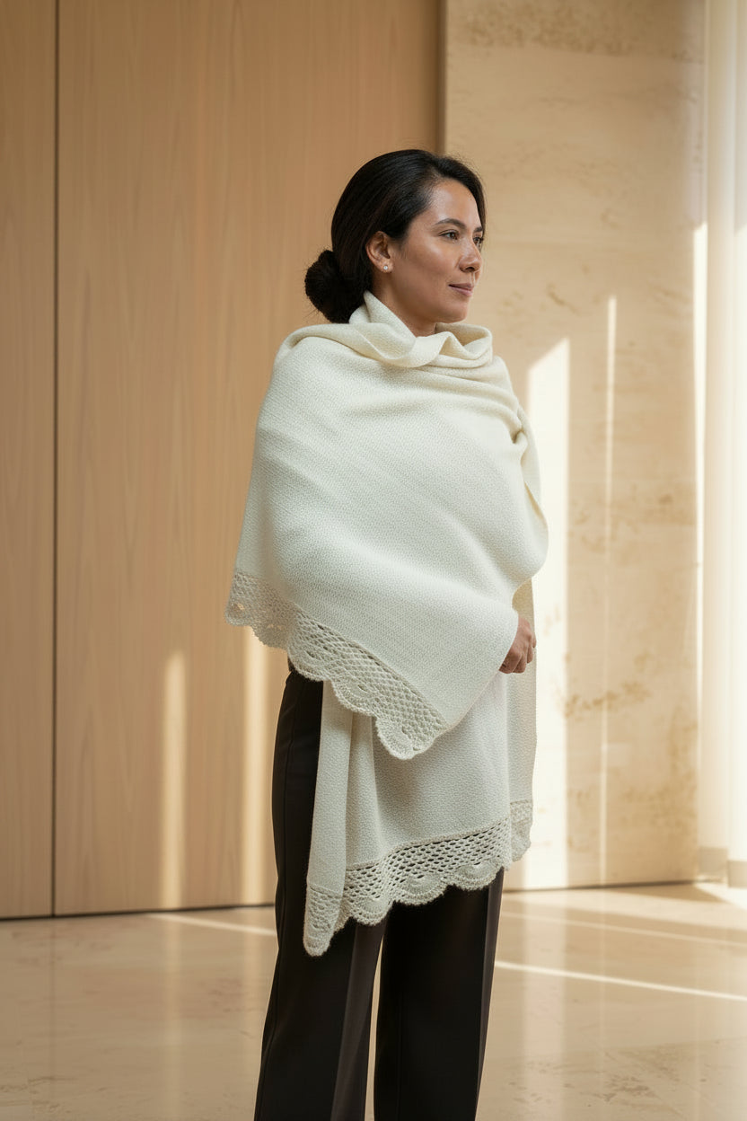 A woman wearing a cream-colored knit shawl with a scalloped edge.