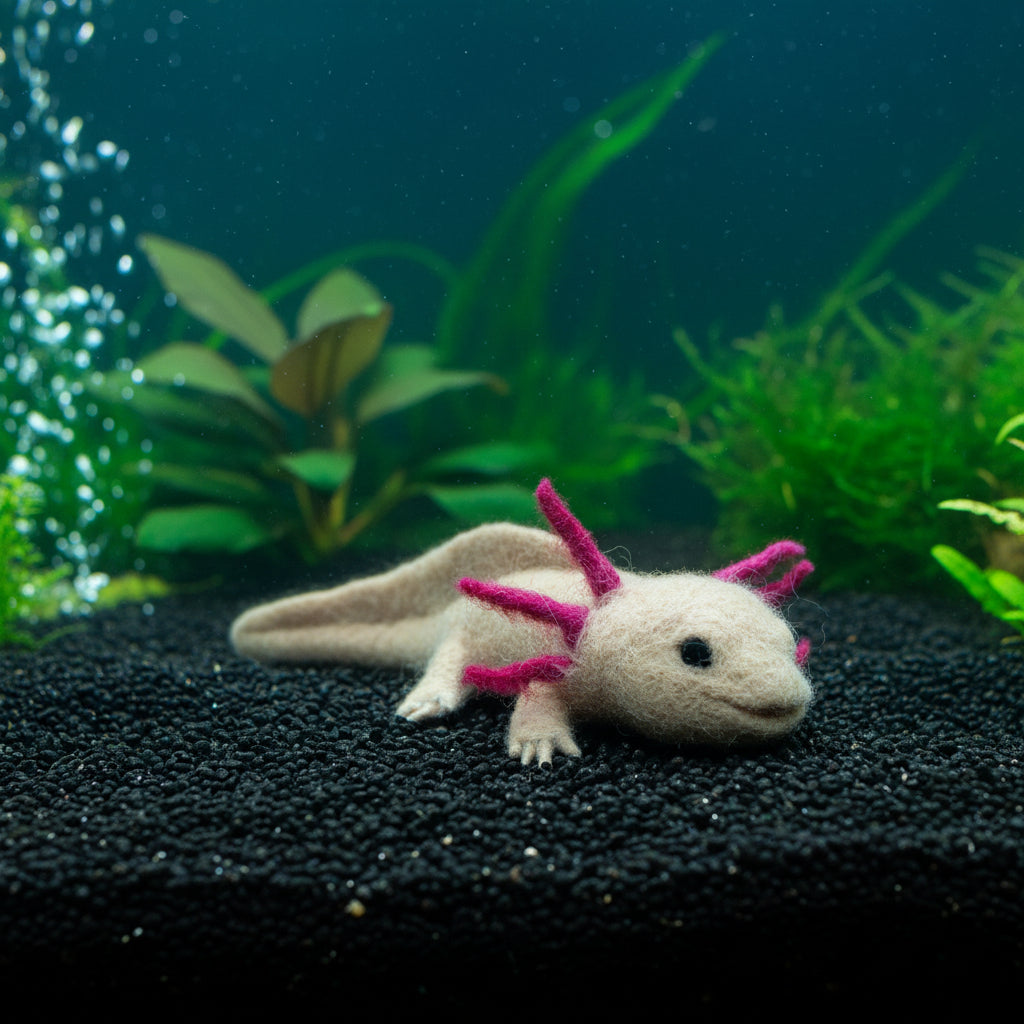 A felted alpaca sculpture resembling an Axolotl with beige body and pink protrusions on its back.