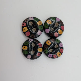 Four round buttons with floral patterns on a white background