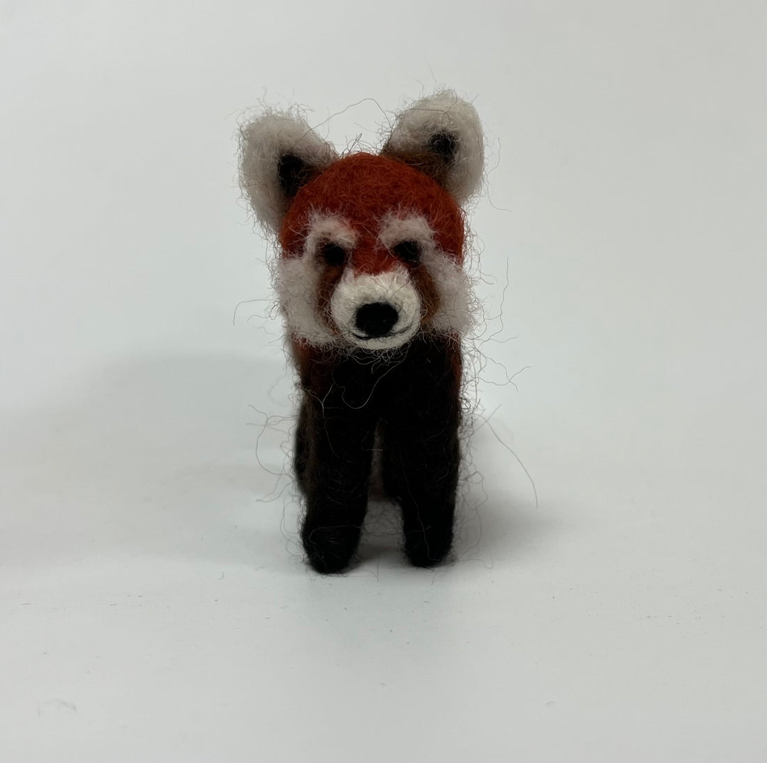 A handcrafted felted wool toy red panda standing upright against a plain white background.