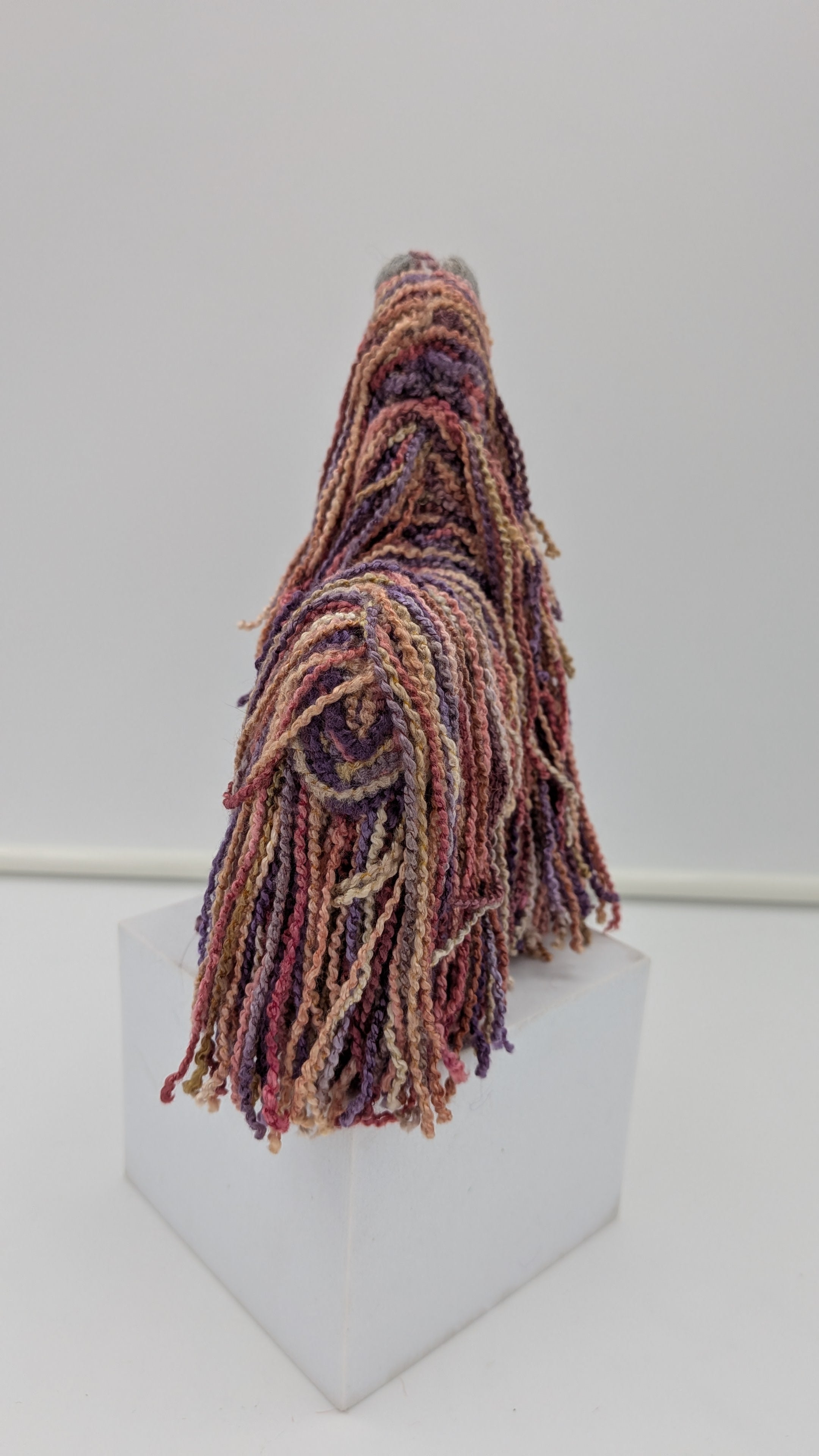 Multicolored tassel on a white pedestal against a white background