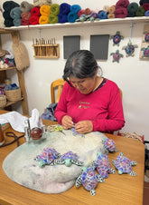 Woman working on colorful hand-painted lanart alpaca turtles in a craft workshop.