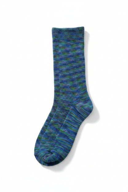 A single knit sock in a variegated blue and green pattern, laid flat on top of a brown cardboard box.