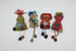 A group of handmade felt fabric creatures or dolls arranged on a plain white background. The figures are made from various colored felt materials with embroidered faces, yarn hair, and small dangling accessories.