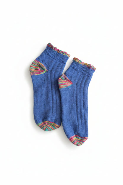 Pair of blue socks with colorful cuffs on a dark surface