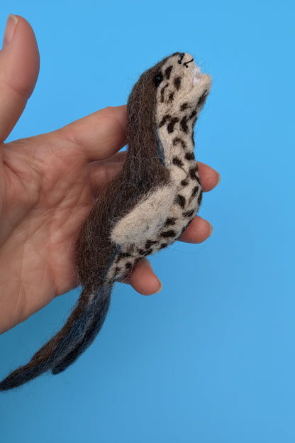 Needle-felted alpaca leopard seal art sculpture on a neutral background.