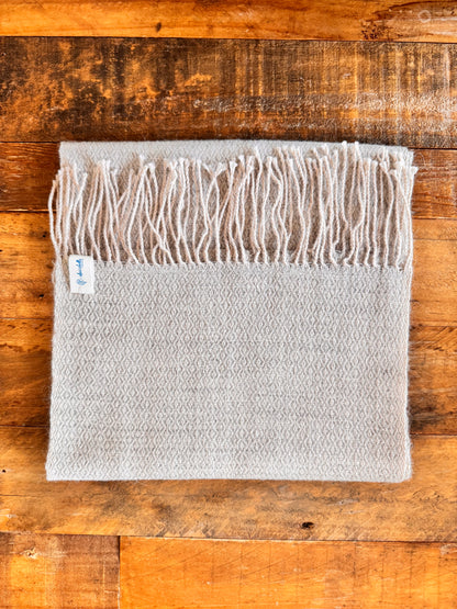Gray textured lightweight
 with fringe on a wooden surface