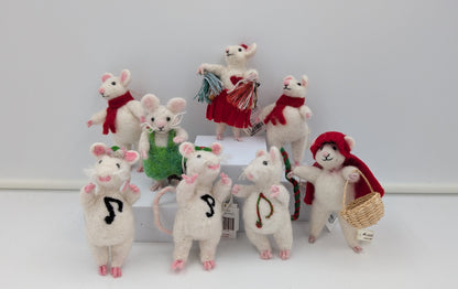 A group of small white plush mouse figurines dressed in holiday-style clothing, including red scarves, a green dress, and a red hat, arranged on a white surface against a light gray background.