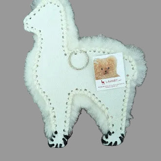 White plush fur alpaca with a tag on a wooden surface