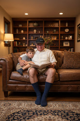 Man sitting on a chair wearing blue socks in an indoor setting with wooden floors and furniture.