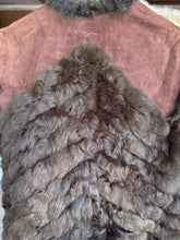 A handmade vest made from brown fur with a dusty pink suede-like front panel, hanging.