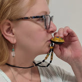 Person holding a small yellow object to their mouth against a plain background
