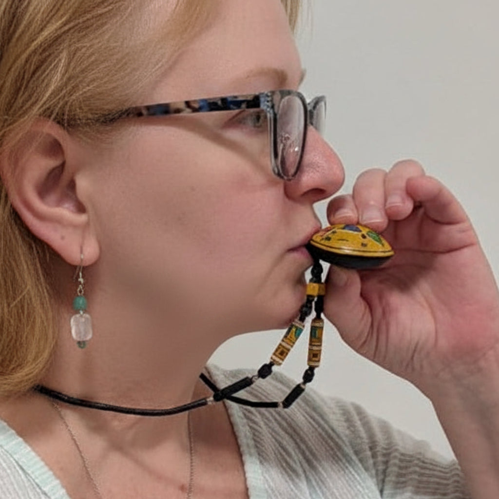 Person holding a small yellow object to their mouth against a plain background