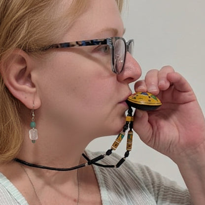 Person holding a small yellow object to their mouth against a plain background