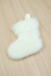 White fluffy alpaca fur christmas stocking on a light wooden surface