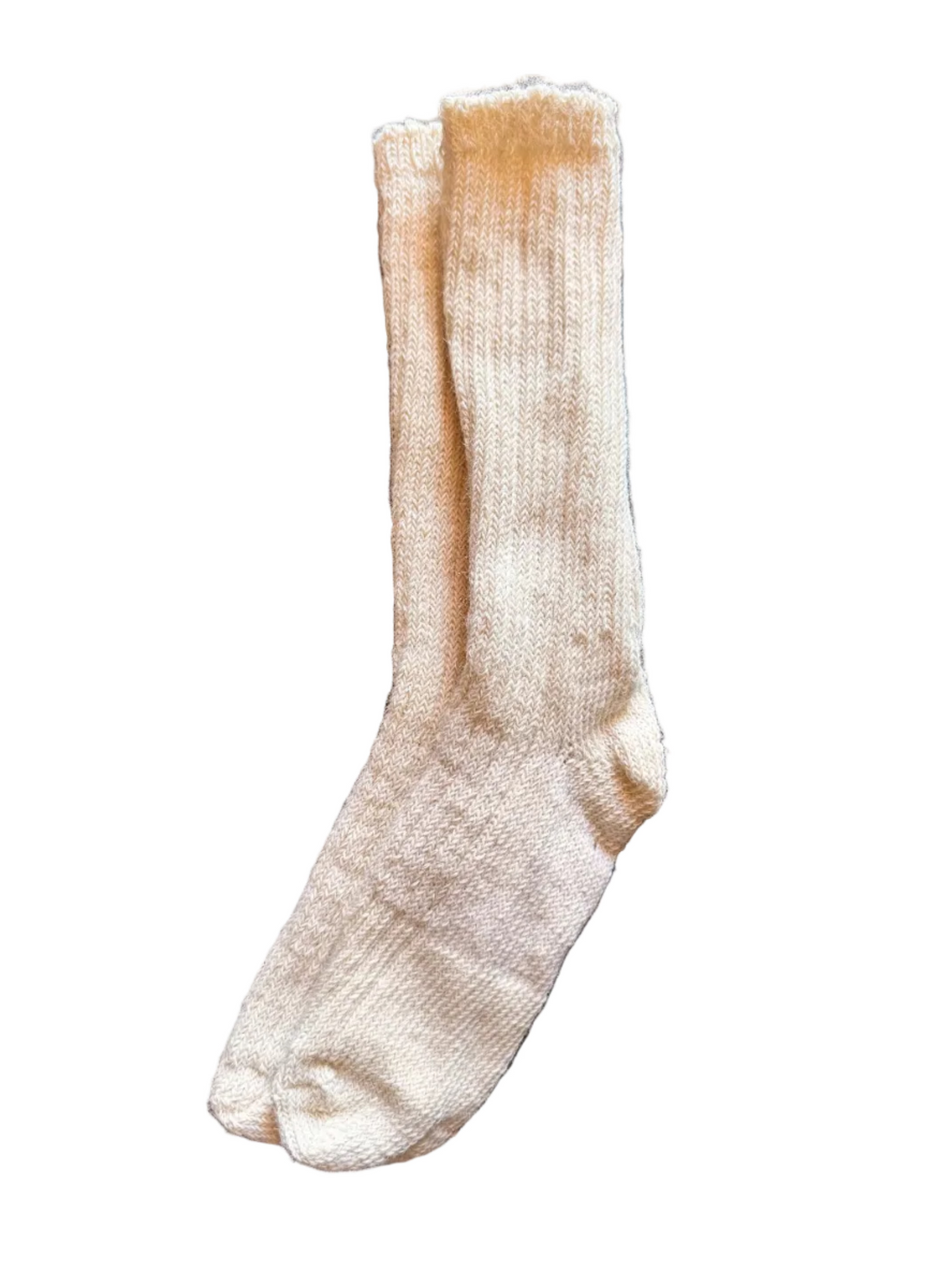 A single cream-colored knit sock laid flat on a dark gray stone tile surface.