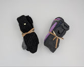 Two pairs of folded socks on a white background. The left pair is black with a small gold button and tied with a tan ribbon.