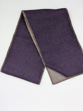 A folded dark purple wool scarf with a contrasting brown border, displayed on a clean white surface.