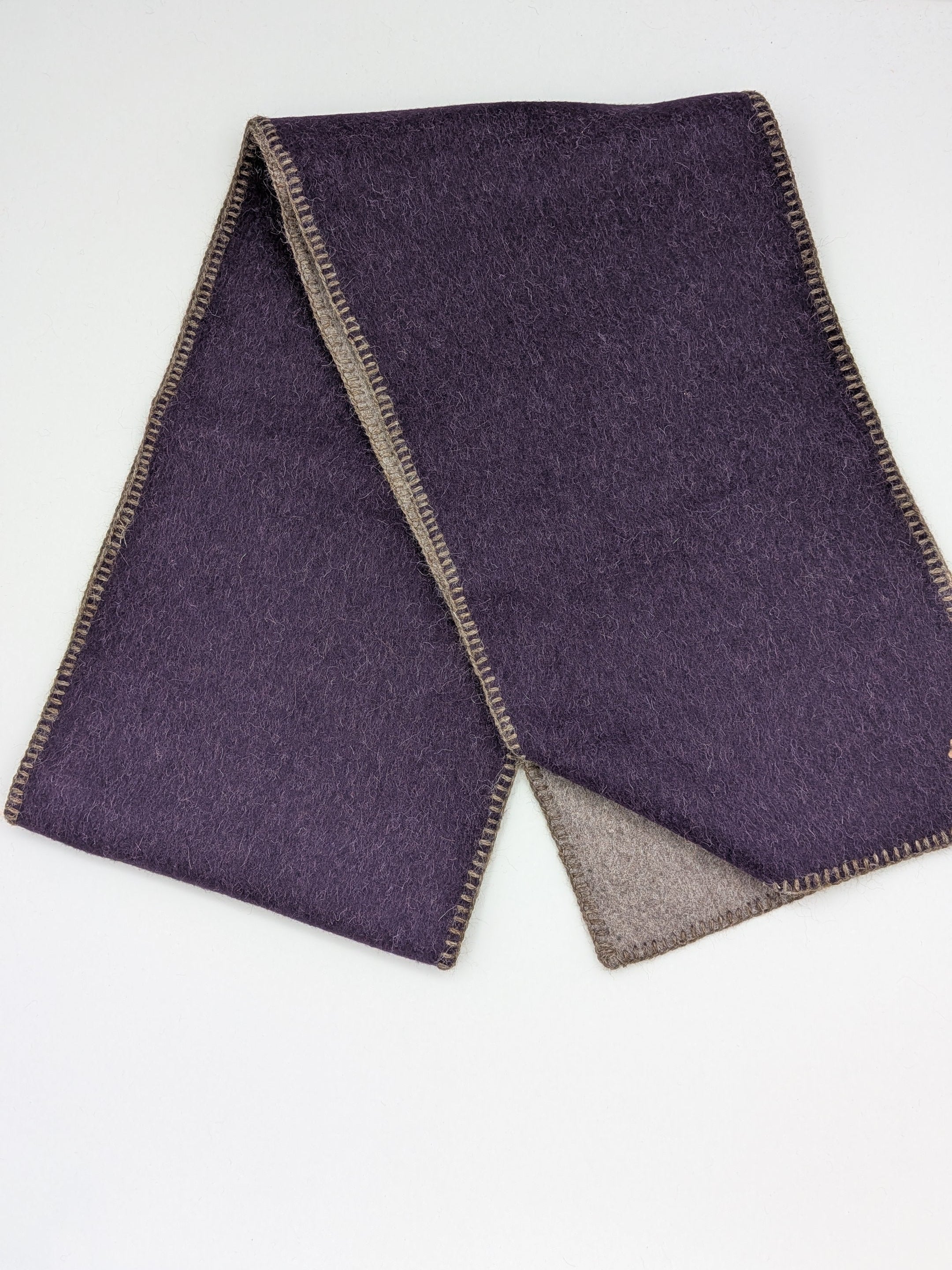 A folded dark purple wool scarf with a contrasting brown border, displayed on a clean white surface.