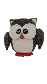A plush owl toy made from textured knit fabric, featuring a dark gray and black body, cream-colored face and belly, and a small red beak and feet, set against a plain light gray background.