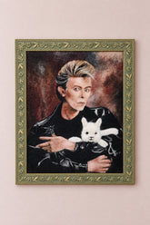 Framed needle-felted alpaca fiber portrait of a David Bowie and his alpaca hanging on a wall.