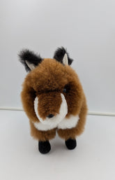 A plush toy fox with brown fur, a white muzzle and chest, and black ears, eyes, and paws, standing against a plain white background.
