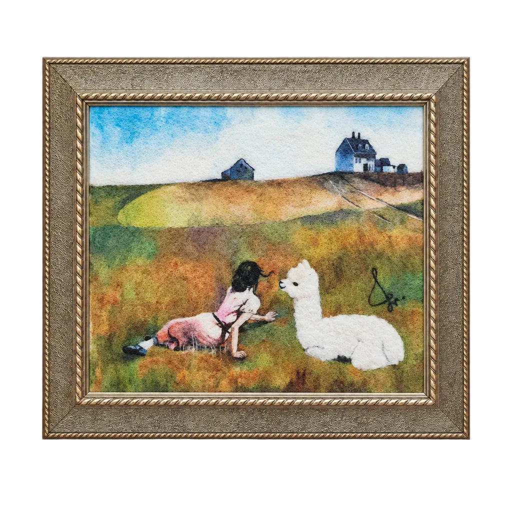Framed artwork of a dog and a llama sitting on a grassy hill with houses in the background.