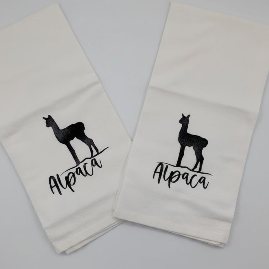 Two white towels with black llama graphics and text on a light gray background