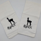 Two white towels with black llama graphics and text on a light gray background
