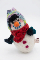 A needle-felted alpaca fiber snowman sculpture with a red hat and carrot nose, leaning against a white background.