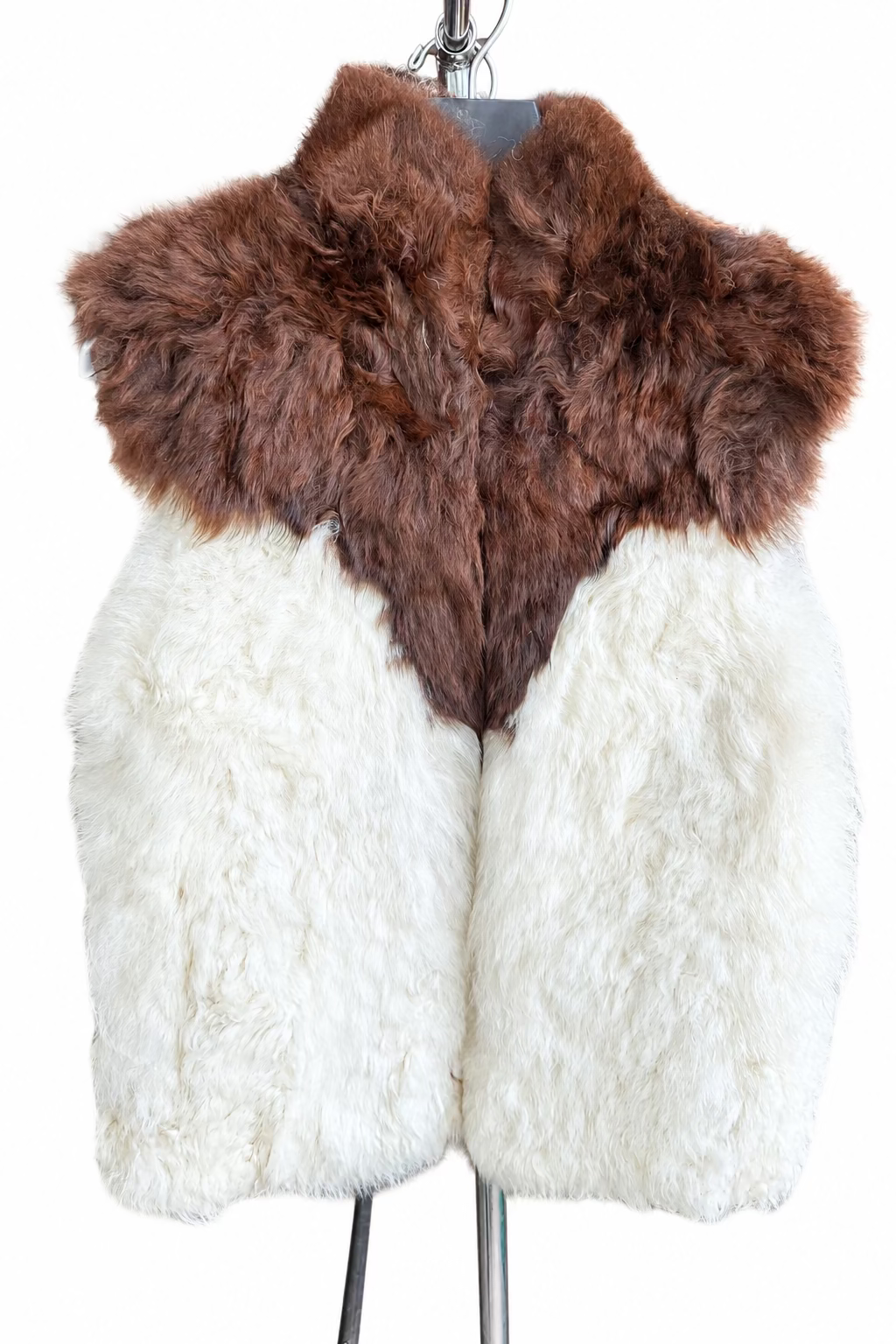 A shaggy alpaca-fur vest outerwear piece displayed on a hanger. The top section is medium brown and the lower body is off-white/cream, creating a two-tone effect.