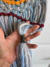 hand holding detail of macrame wall art piece
